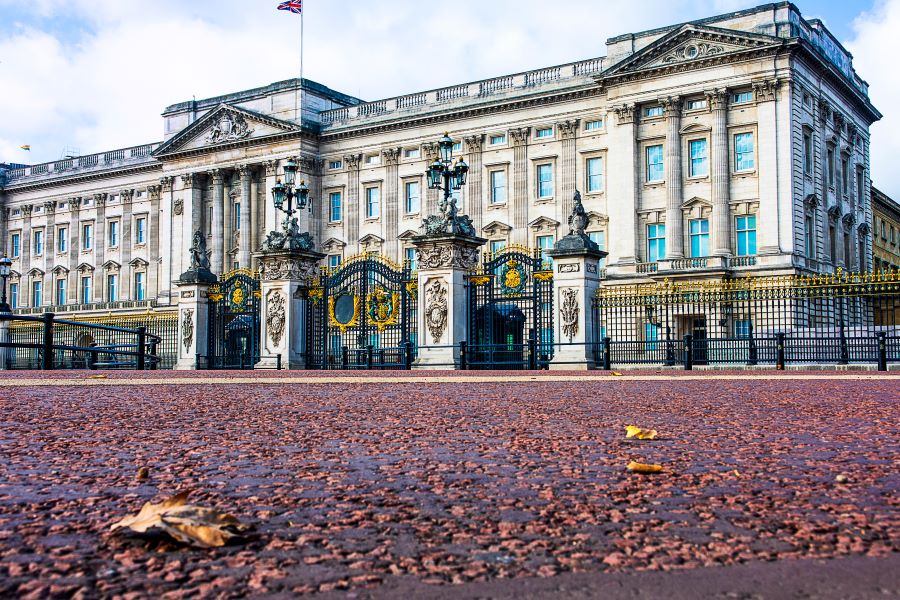 image of famous Buckingham Palace in London, England on a rainy day with a few leaves on the cobblestone in front of the renowned gated entrace