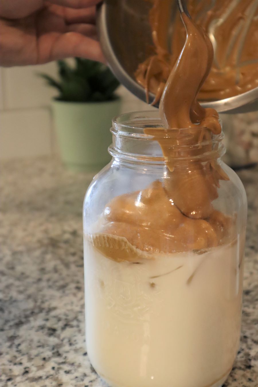 Pouring Whipped Coffee over Iced Milk