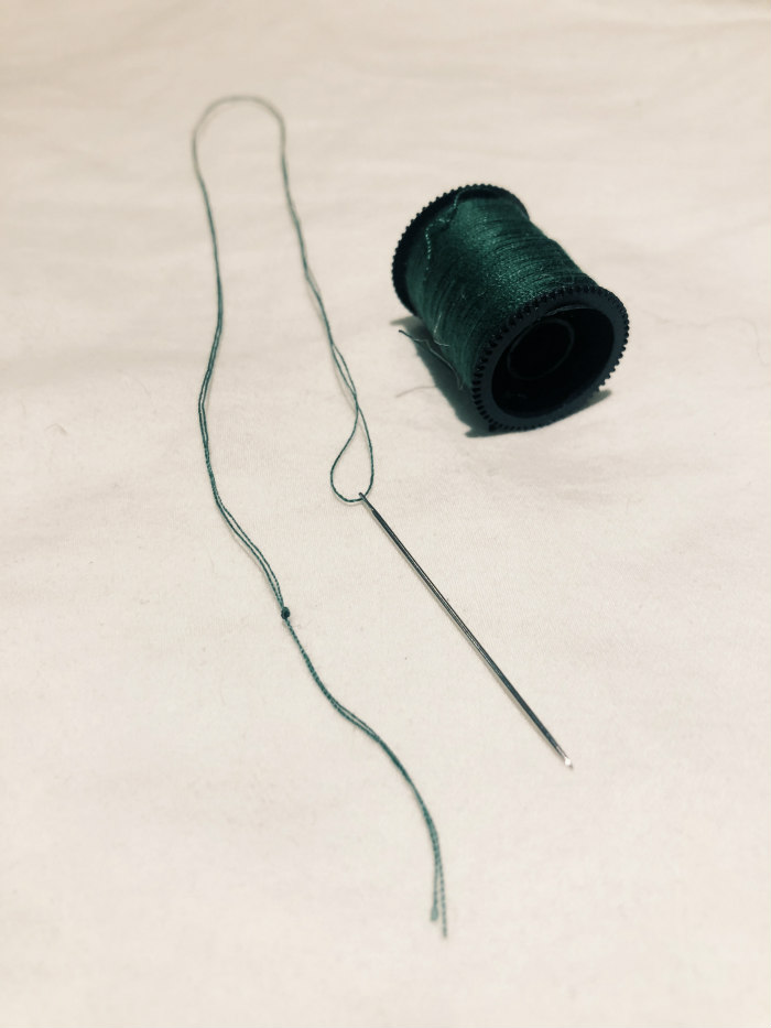 green thread and sewing needle